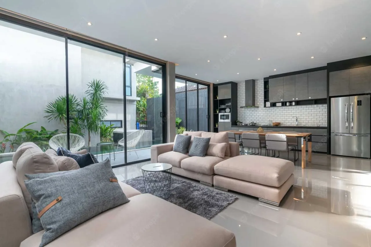 Another elegant living room at L&T Island Cove showcasing a stylish combination of modern and rustic design elements, a plush sofa, large windows, and a warm wooden accent wall.